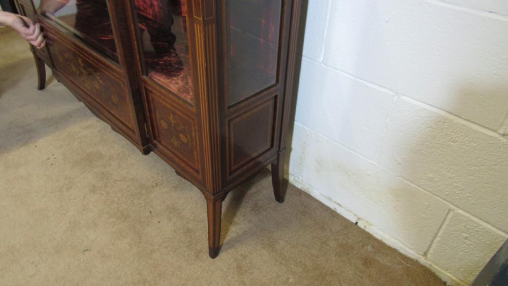 An Edwardian fiddleback mahogany display cabinet featuring glazed doors, detailed floral marquetry inlay on the lower panels, and square tapered legs. View XIX
