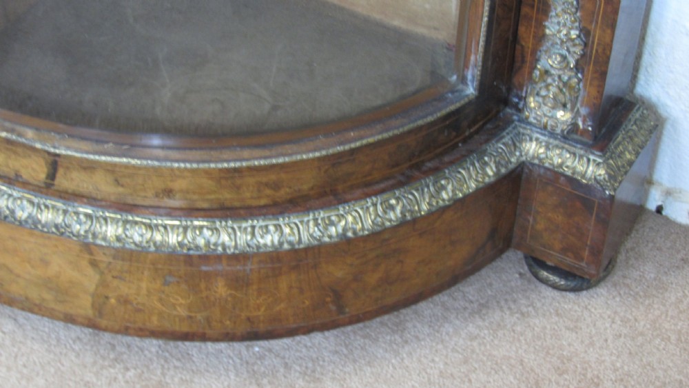 A Victorian burr walnut credenza featuring a central inlaid panel door flanked by two curved glazed display cupboards with gilt brass mounts. View VI