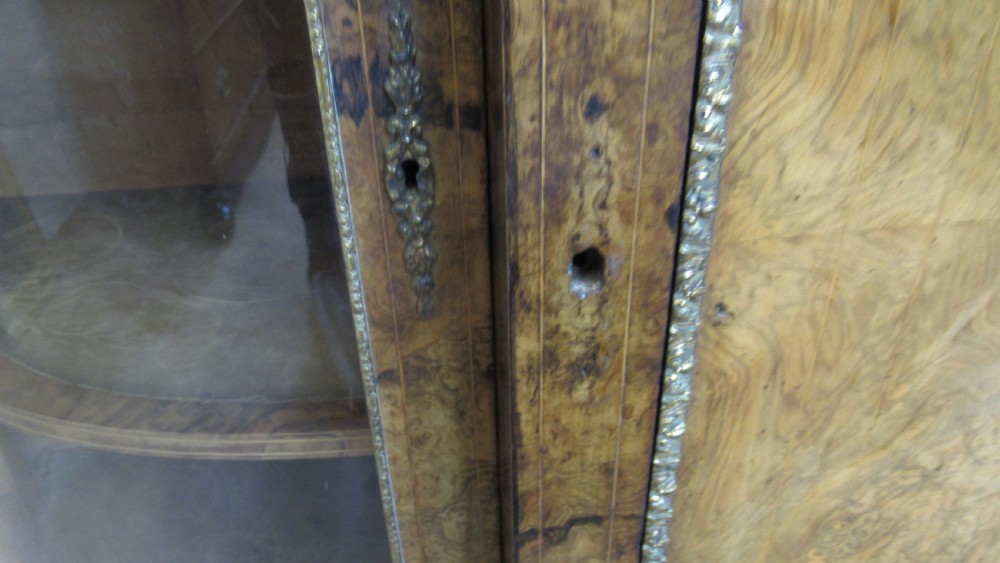 A Victorian burr walnut credenza featuring a central inlaid panel door flanked by two curved glazed display cupboards with gilt brass mounts. View XIX
