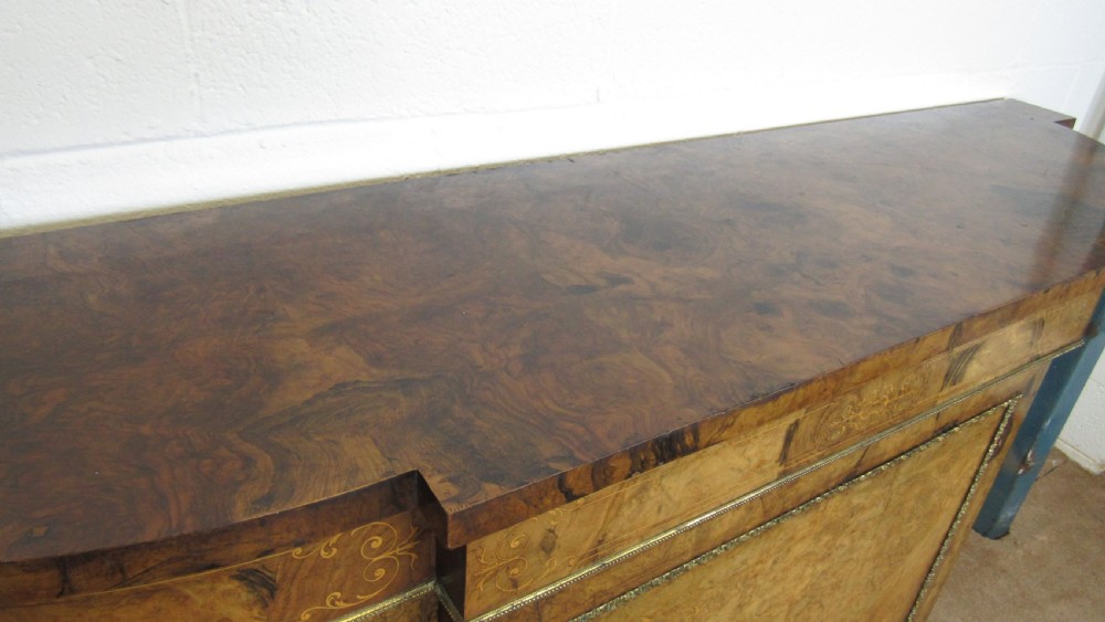 A Victorian burr walnut credenza featuring a central inlaid panel door flanked by two curved glazed display cupboards with gilt brass mounts. View XXIV