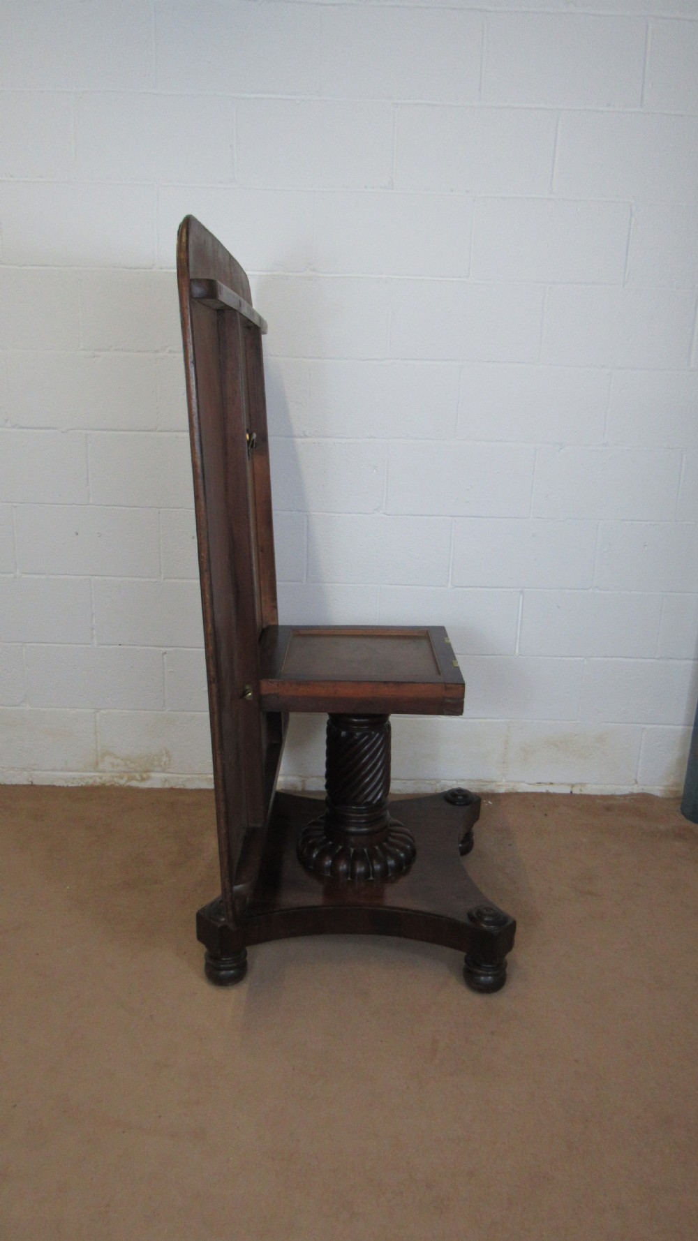 A 19th-century mahogany tilt-top centre table positioned vertically to show its flame-veneered surface and crossbanded border on a central pedestal base. View V