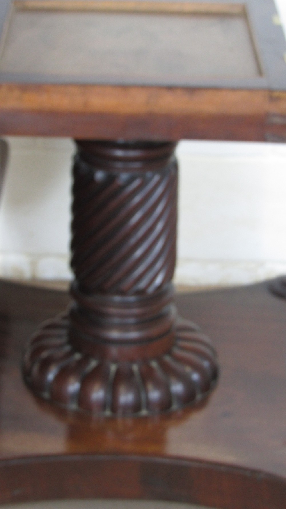 A 19th-century mahogany tilt-top centre table positioned vertically to show its flame-veneered surface and crossbanded border on a central pedestal base. View VII