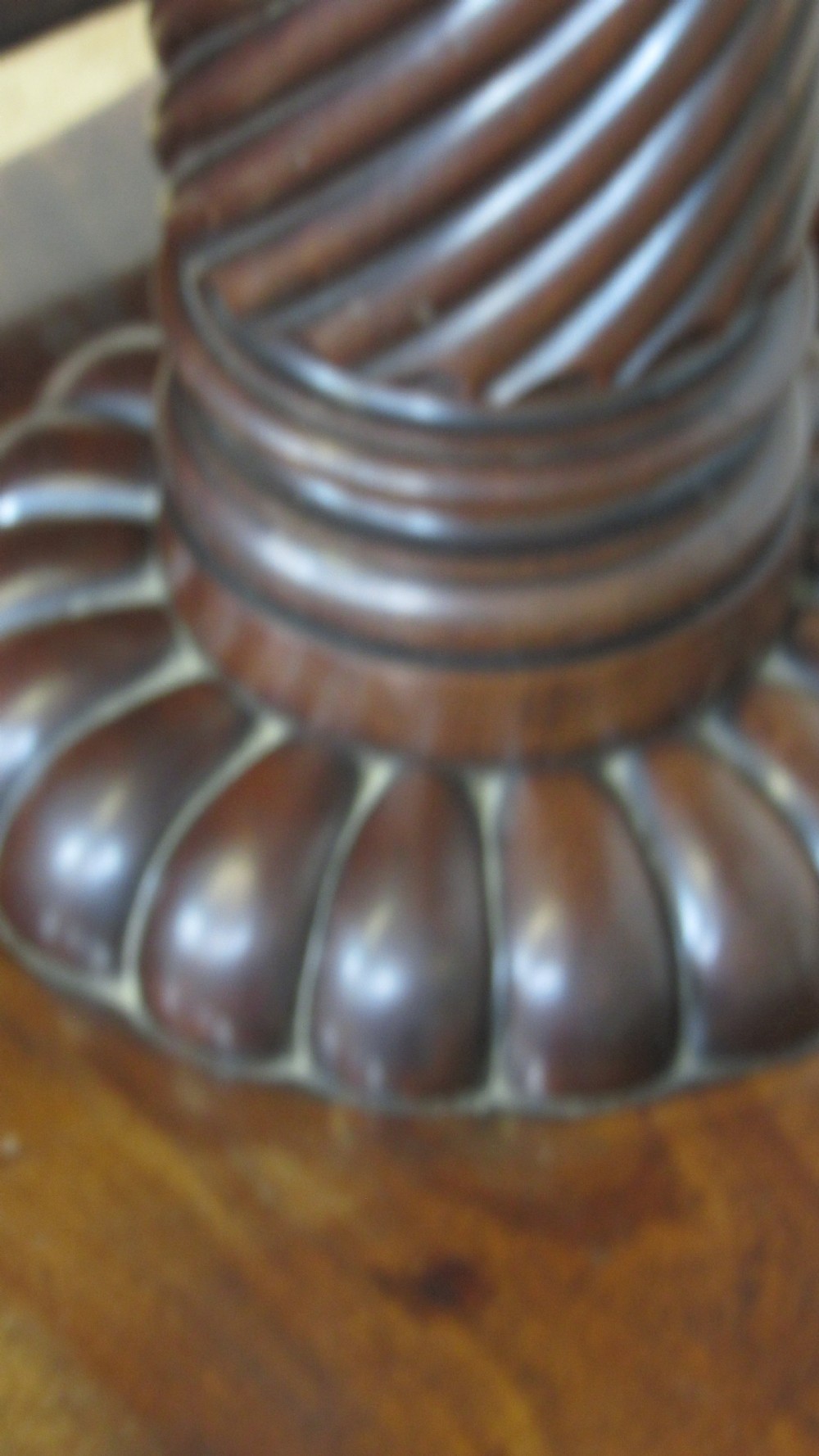A 19th-century mahogany tilt-top centre table positioned vertically to show its flame-veneered surface and crossbanded border on a central pedestal base. View XI