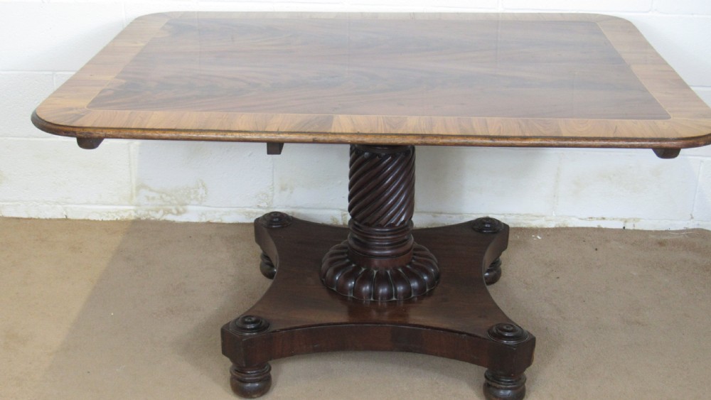 A 19th-century mahogany tilt-top centre table positioned vertically to show its flame-veneered surface and crossbanded border on a central pedestal base. View XIII
