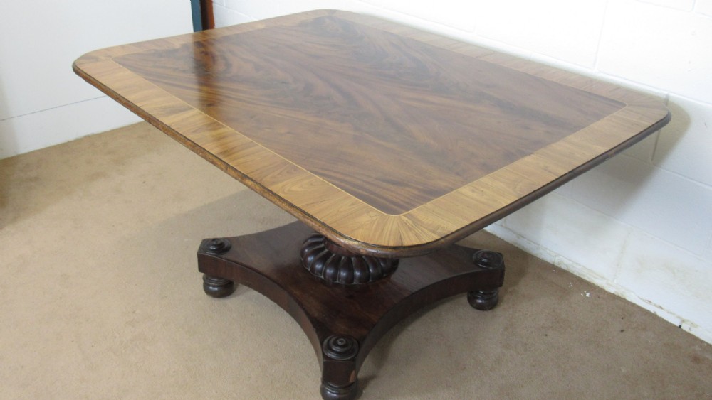 A 19th-century mahogany tilt-top centre table positioned vertically to show its flame-veneered surface and crossbanded border on a central pedestal base. View XIV