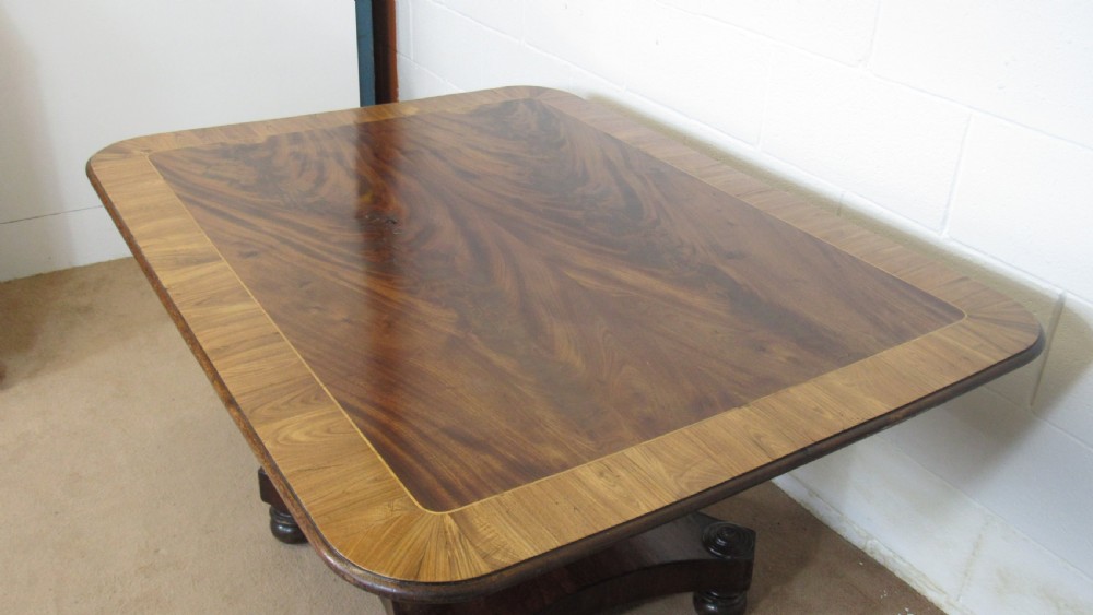 A 19th-century mahogany tilt-top centre table positioned vertically to show its flame-veneered surface and crossbanded border on a central pedestal base. View XV
