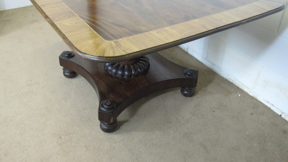 A 19th-century mahogany tilt-top centre table positioned vertically to show its flame-veneered surface and crossbanded border on a central pedestal base. View XVI