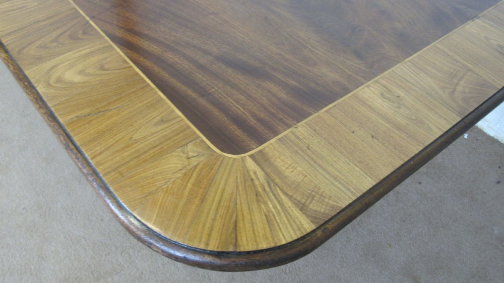 A 19th-century mahogany tilt-top centre table positioned vertically to show its flame-veneered surface and crossbanded border on a central pedestal base. View XVII