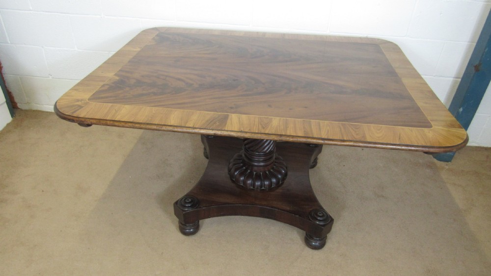 A 19th-century mahogany tilt-top centre table positioned vertically to show its flame-veneered surface and crossbanded border on a central pedestal base. View XIX