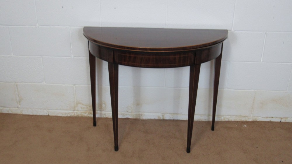 A Georgian mahogany demi-lune card table with linear string inlay and tapered square legs.