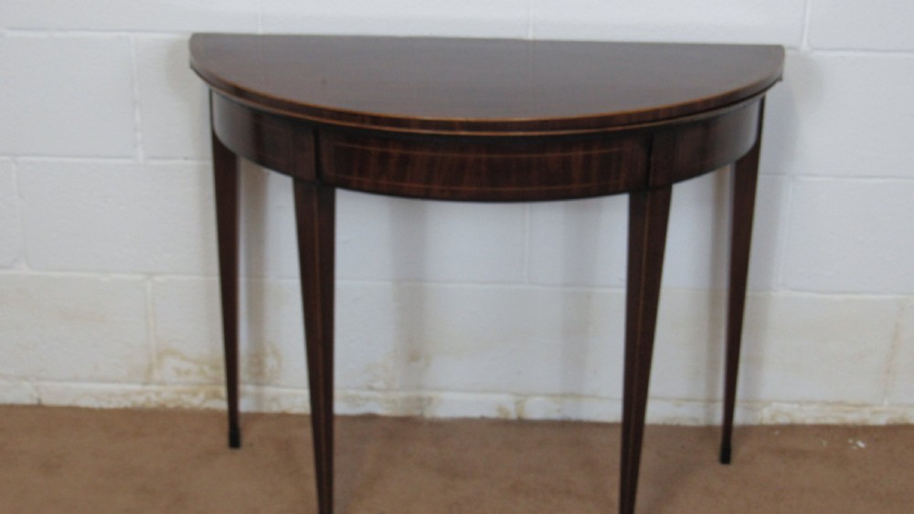 A Georgian mahogany demi-lune card table with linear string inlay and tapered square legs. View II
