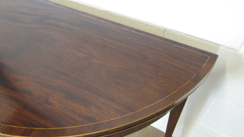 A Georgian mahogany demi-lune card table with linear string inlay and tapered square legs. View V