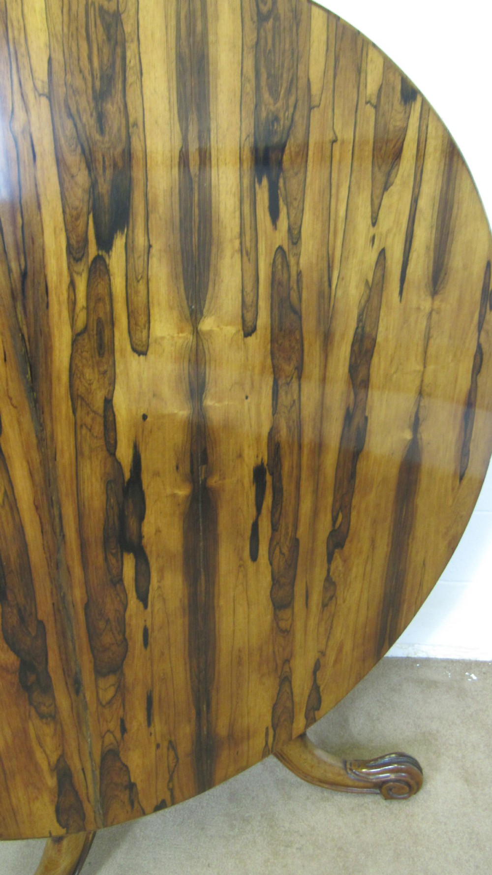 A circular antique rosewood tilt-top table shown in a vertical tilted position, displaying figured timber grain and a carved tripod base. View II