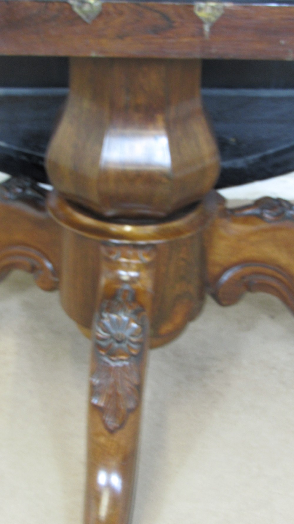 A circular antique rosewood tilt-top table shown in a vertical tilted position, displaying figured timber grain and a carved tripod base. View IX