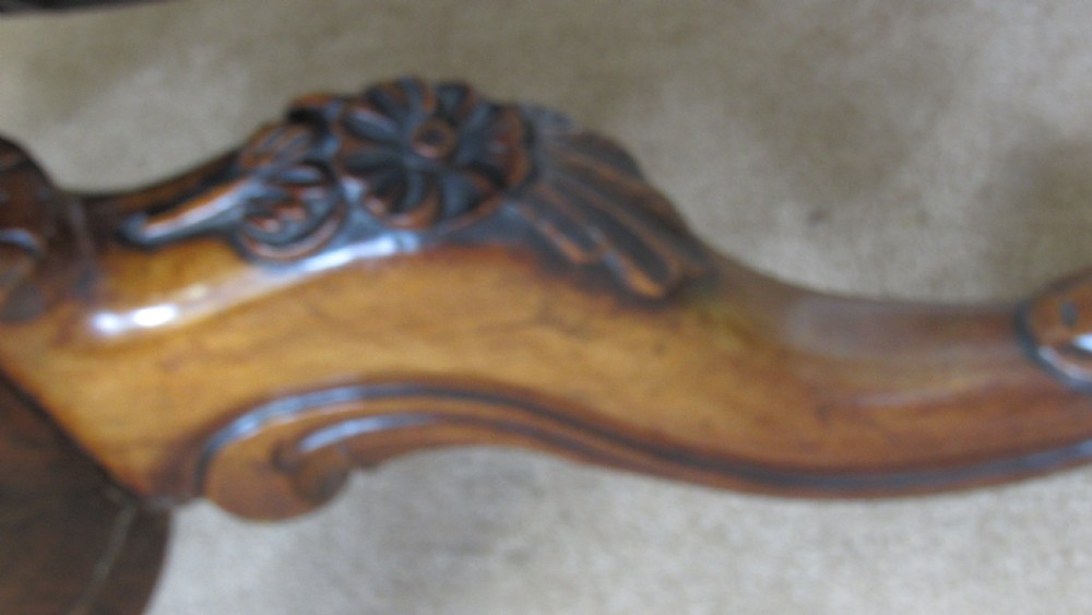 A circular antique rosewood tilt-top table shown in a vertical tilted position, displaying figured timber grain and a carved tripod base. View XI