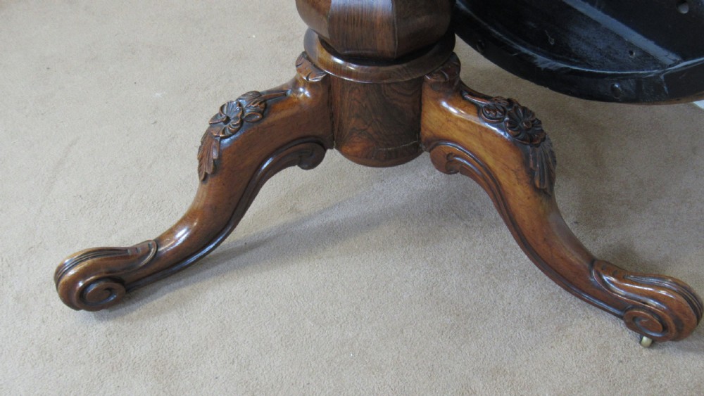 A circular antique rosewood tilt-top table shown in a vertical tilted position, displaying figured timber grain and a carved tripod base. View XII