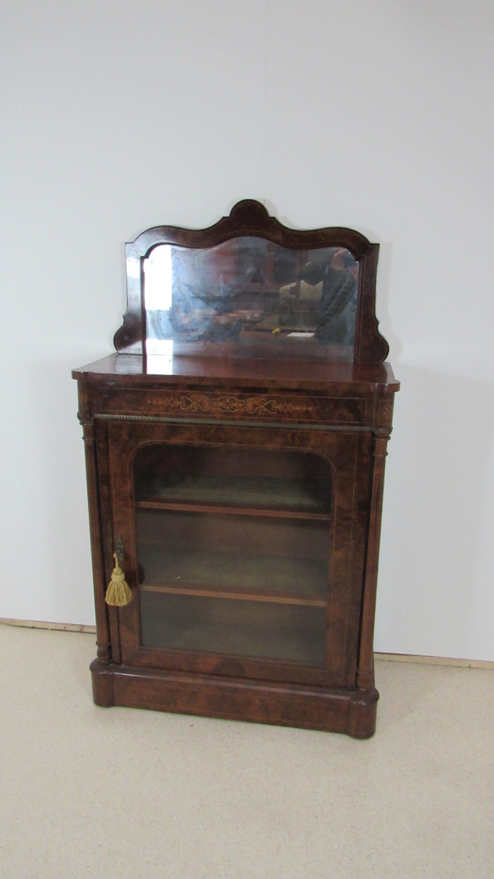Victorian burr walnut pier cabinet featuring a glazed single door, scrollwork marquetry inlay, side columns, and an arched mirror back. View II