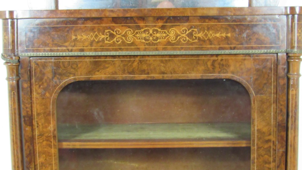 Victorian burr walnut pier cabinet featuring a glazed single door, scrollwork marquetry inlay, side columns, and an arched mirror back. View III