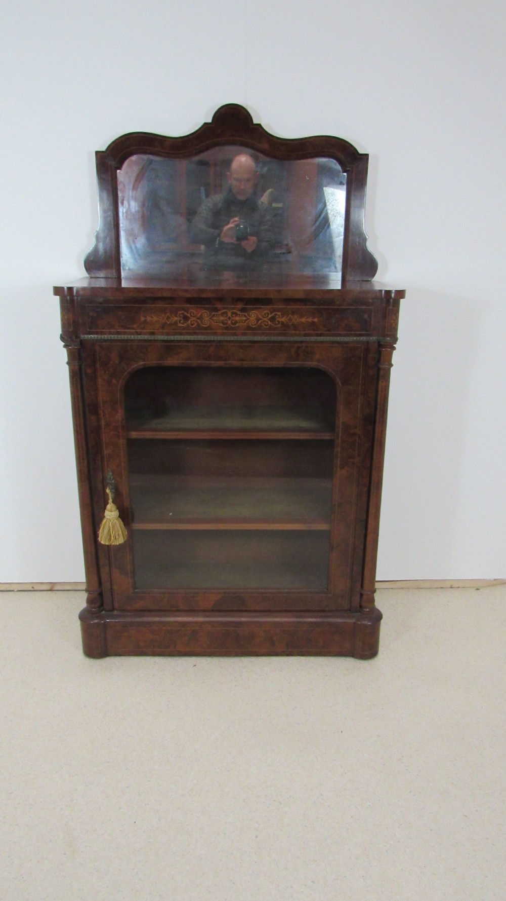 Victorian burr walnut pier cabinet featuring a glazed single door, scrollwork marquetry inlay, side columns, and an arched mirror back. View V