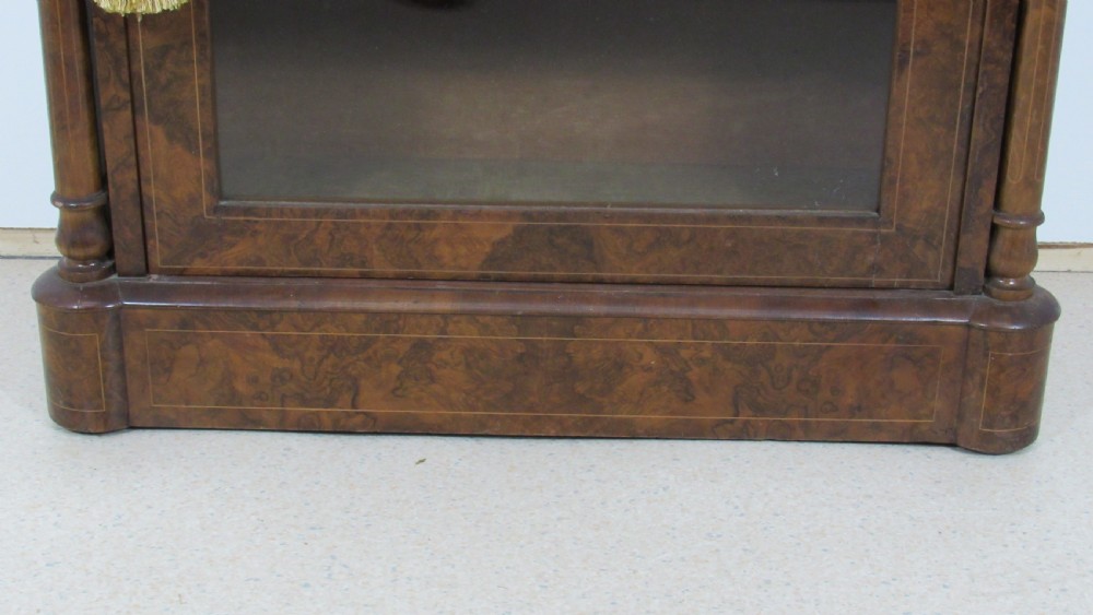 Victorian burr walnut pier cabinet featuring a glazed single door, scrollwork marquetry inlay, side columns, and an arched mirror back. View VI