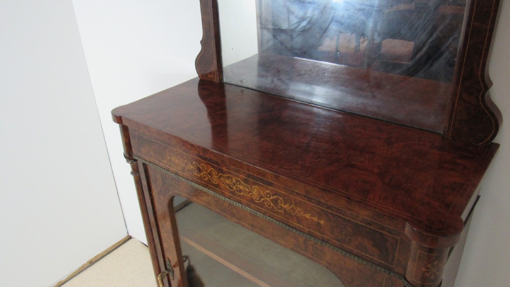 Victorian burr walnut pier cabinet featuring a glazed single door, scrollwork marquetry inlay, side columns, and an arched mirror back. View VIII