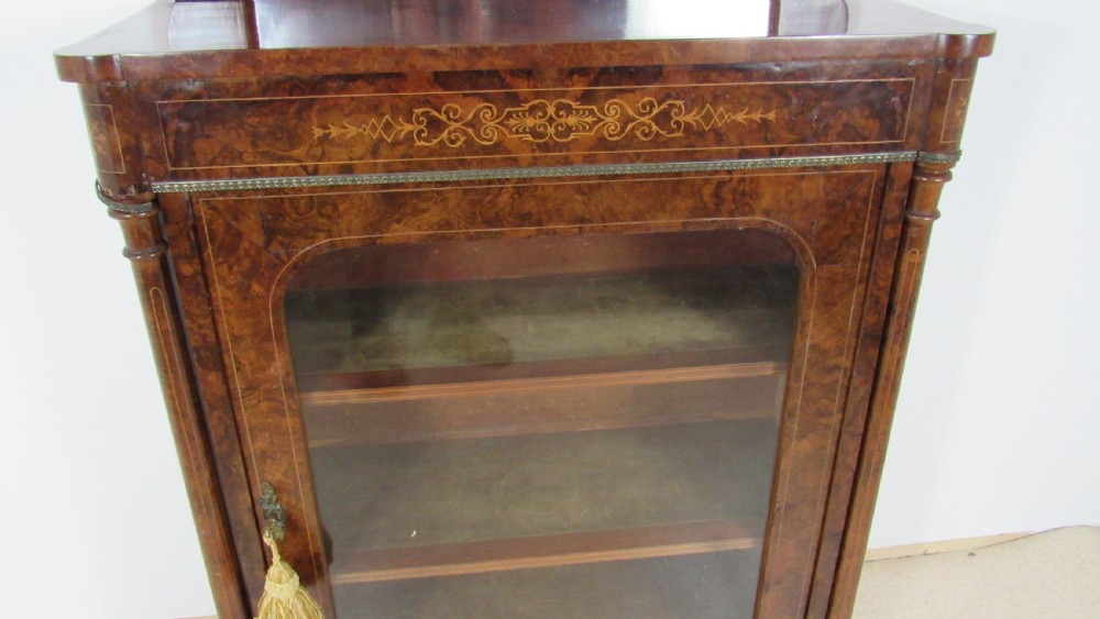 Victorian burr walnut pier cabinet featuring a glazed single door, scrollwork marquetry inlay, side columns, and an arched mirror back. View XI