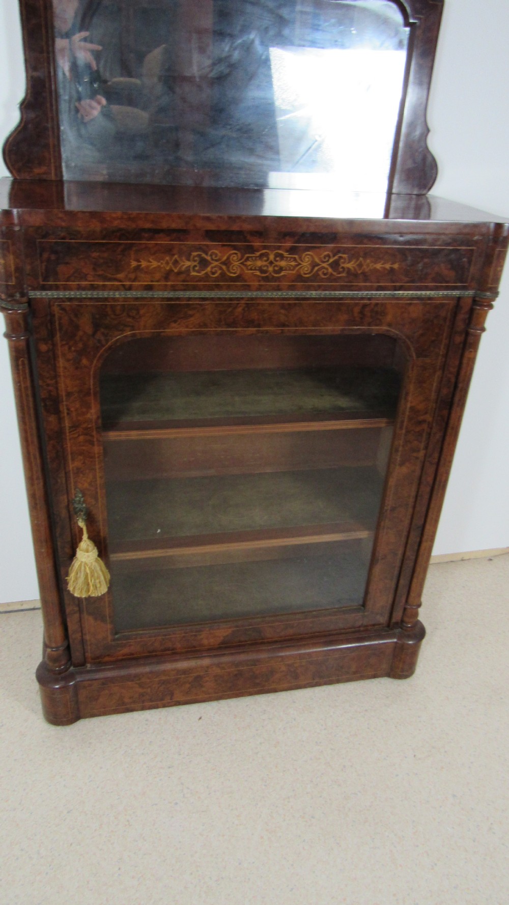 Victorian burr walnut pier cabinet featuring a glazed single door, scrollwork marquetry inlay, side columns, and an arched mirror back. View XII