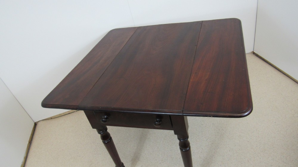 A dark mahogany Pembroke table with two drop leaves, turned legs on brass castors, and a single end drawer with wooden knobs. View VIII