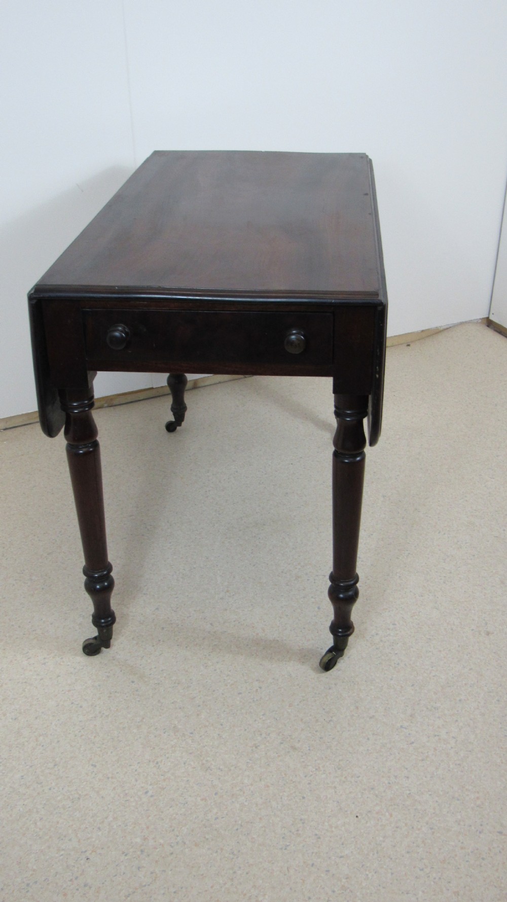 A dark mahogany Pembroke table with two drop leaves, turned legs on brass castors, and a single end drawer with wooden knobs. View XIII