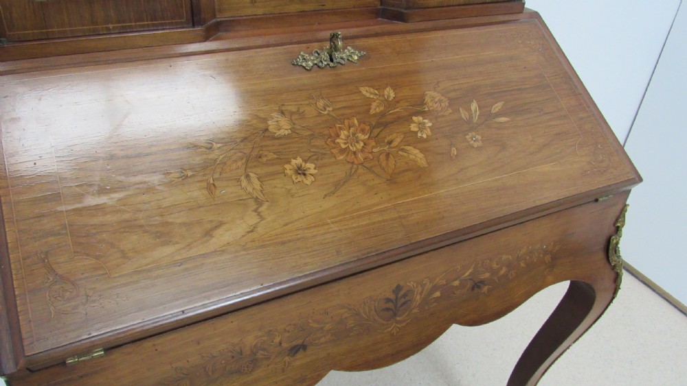 An antique French-style walnut writing bureau with floral marquetry, cabriole legs, brass mounts, and a upper cabinet section featuring small glazed doors and a central mirror. View III