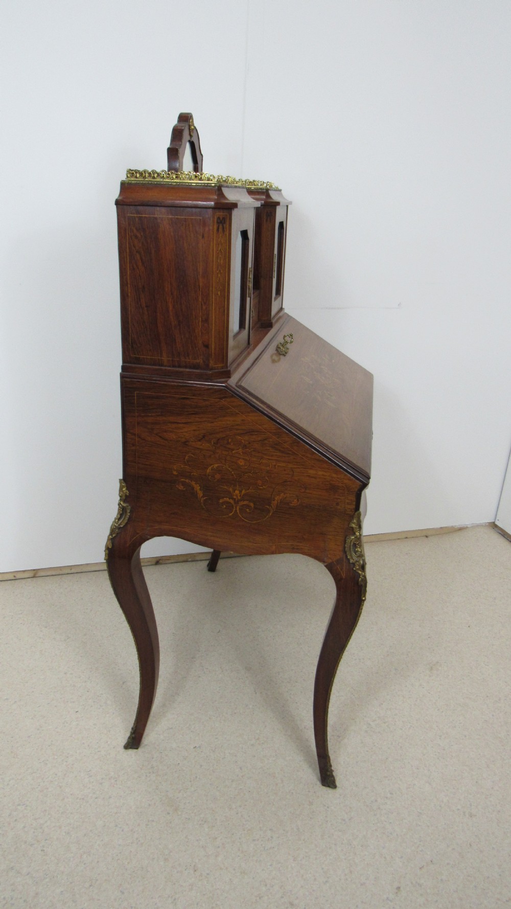 An antique French-style walnut writing bureau with floral marquetry, cabriole legs, brass mounts, and a upper cabinet section featuring small glazed doors and a central mirror. View X