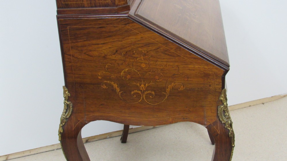 An antique French-style walnut writing bureau with floral marquetry, cabriole legs, brass mounts, and a upper cabinet section featuring small glazed doors and a central mirror. View XI