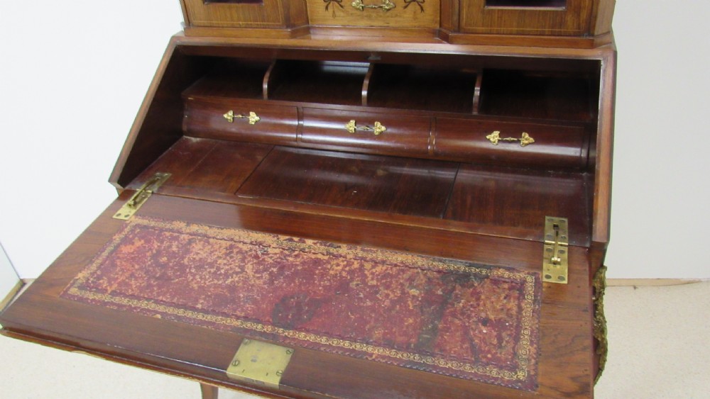 An antique French-style walnut writing bureau with floral marquetry, cabriole legs, brass mounts, and a upper cabinet section featuring small glazed doors and a central mirror. View XV