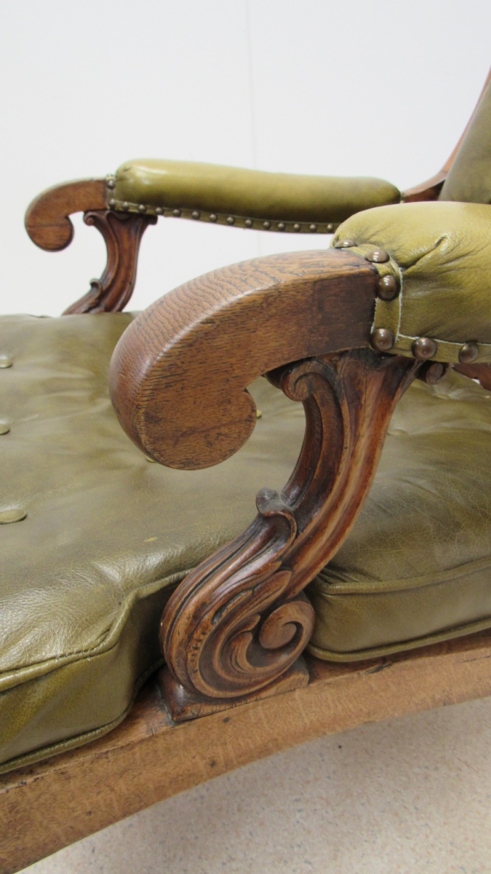 A William IV mahogany library chair upholstered in deep-buttoned olive green leather with padded scroll arms and turned front legs on brass castors. View III