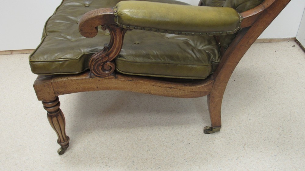A William IV mahogany library chair upholstered in deep-buttoned olive green leather with padded scroll arms and turned front legs on brass castors. View XI