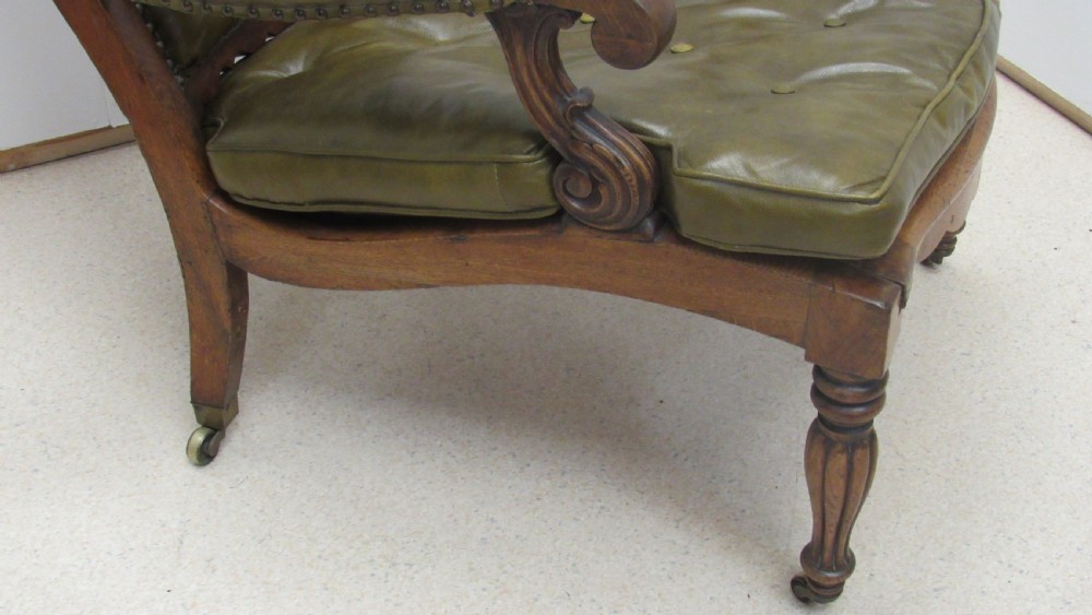 A William IV mahogany library chair upholstered in deep-buttoned olive green leather with padded scroll arms and turned front legs on brass castors. View XIV