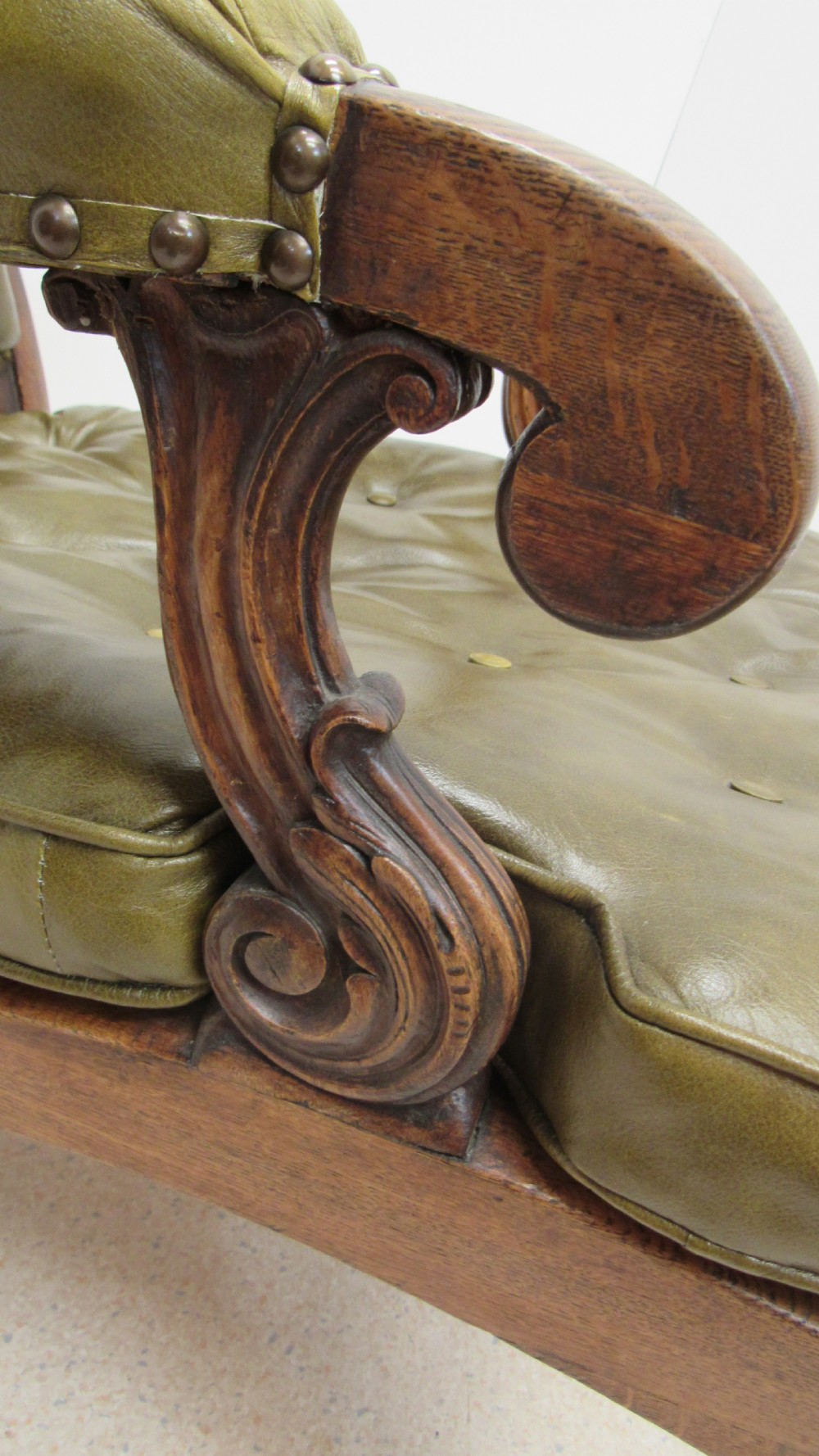 A William IV mahogany library chair upholstered in deep-buttoned olive green leather with padded scroll arms and turned front legs on brass castors. View XVI