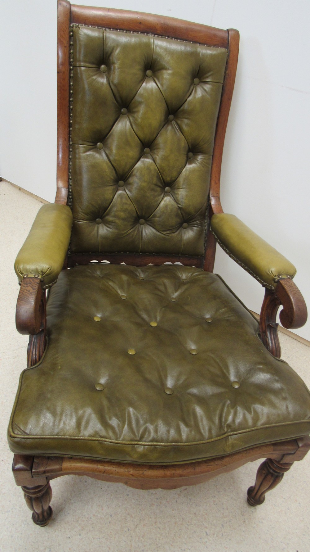 A William IV mahogany library chair upholstered in deep-buttoned olive green leather with padded scroll arms and turned front legs on brass castors. View XVII