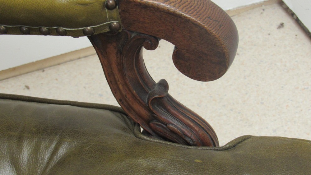 A William IV mahogany library chair upholstered in deep-buttoned olive green leather with padded scroll arms and turned front legs on brass castors. View XVIII