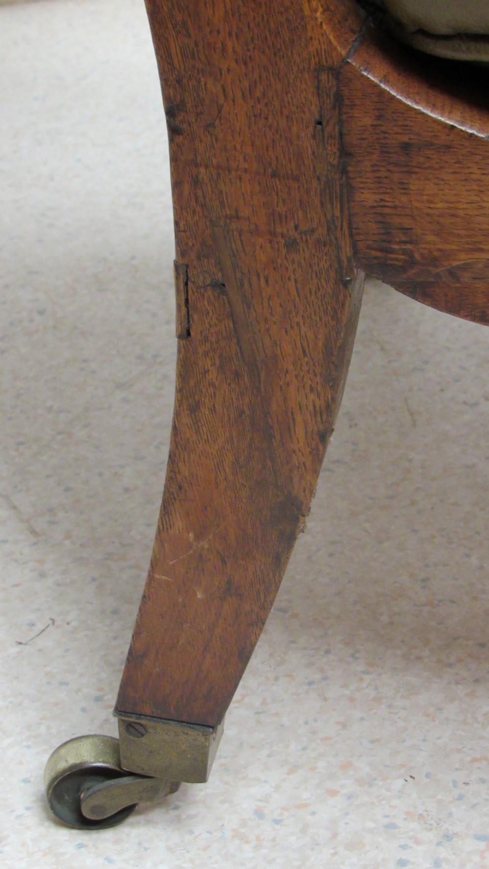 A William IV mahogany library chair upholstered in deep-buttoned olive green leather with padded scroll arms and turned front legs on brass castors. View XIX