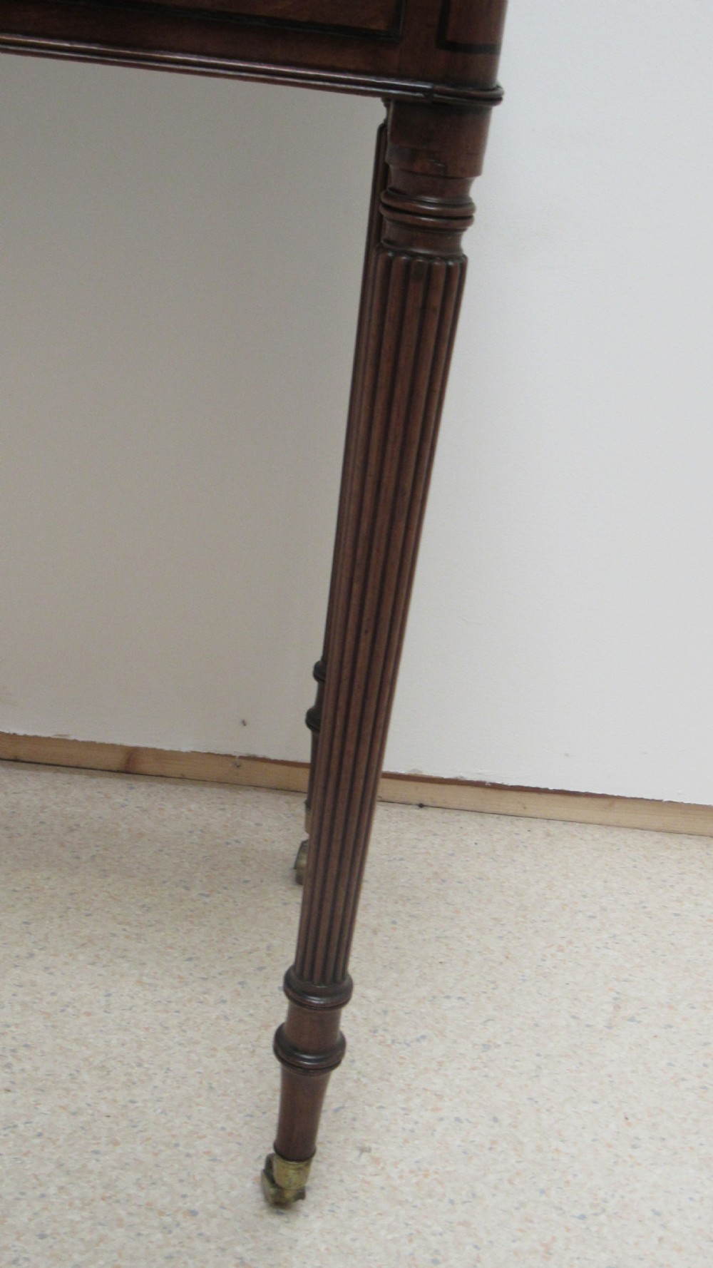 A Regency mahogany chamber table featuring reeded tapered legs on brass castors, a central drawer with wooden knobs, and a hinged lid top. View VIII