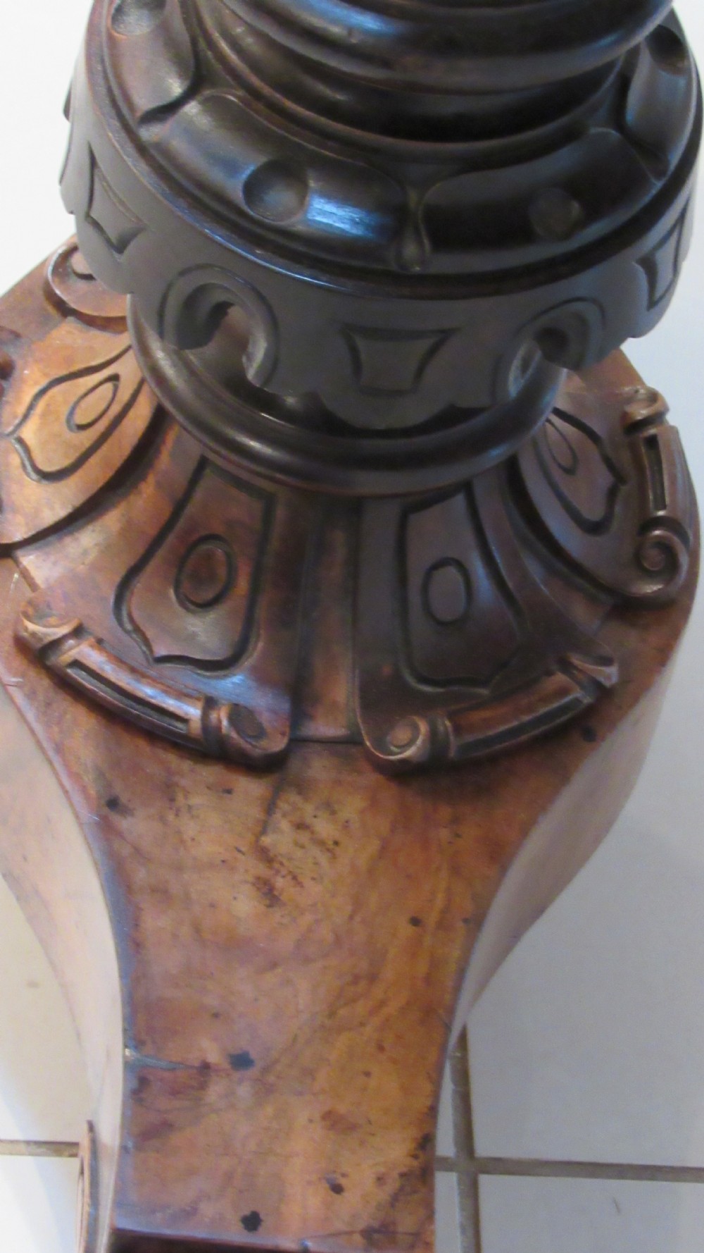 An antique Victorian walnut writing centre table featuring a figured top, deeply carved foliate apron, and carved turned end supports on a trestle base. View XXI