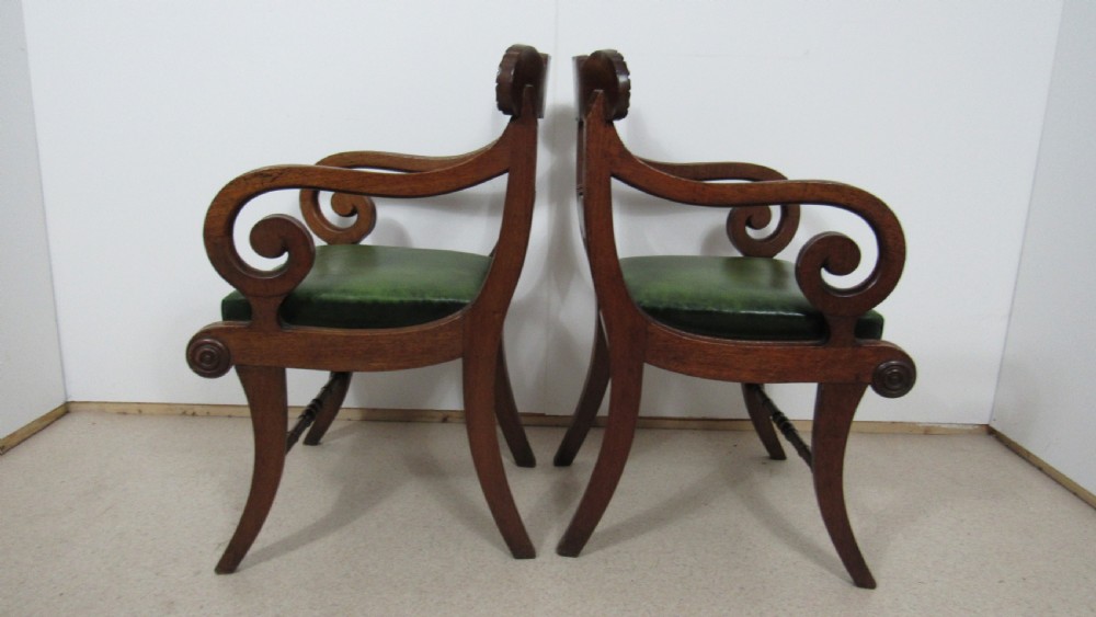 A pair of carved mahogany armchairs featuring scroll-carved top rails, curved armrests, reeded front rails, and green leather upholstered seats. View II