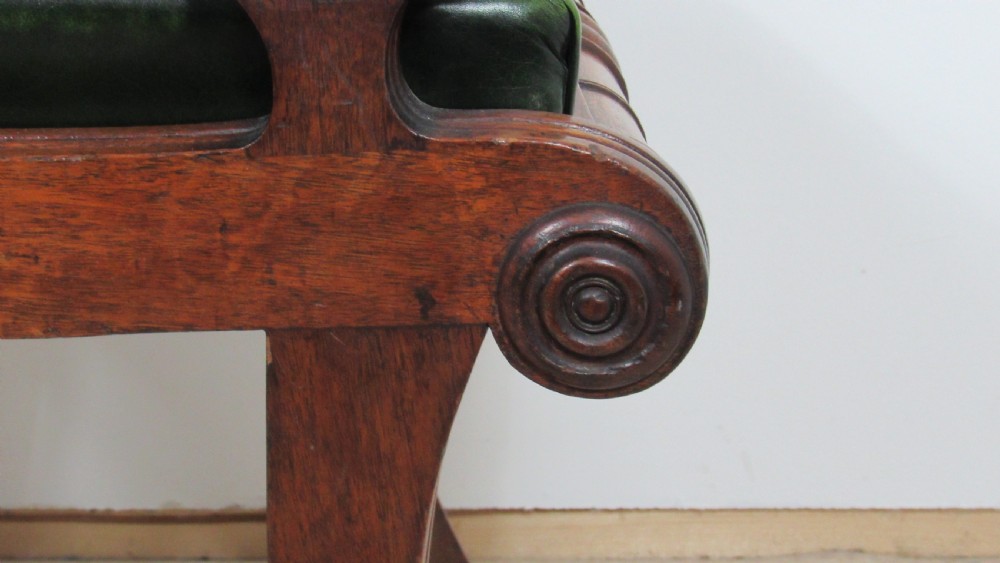 A pair of carved mahogany armchairs featuring scroll-carved top rails, curved armrests, reeded front rails, and green leather upholstered seats. View V
