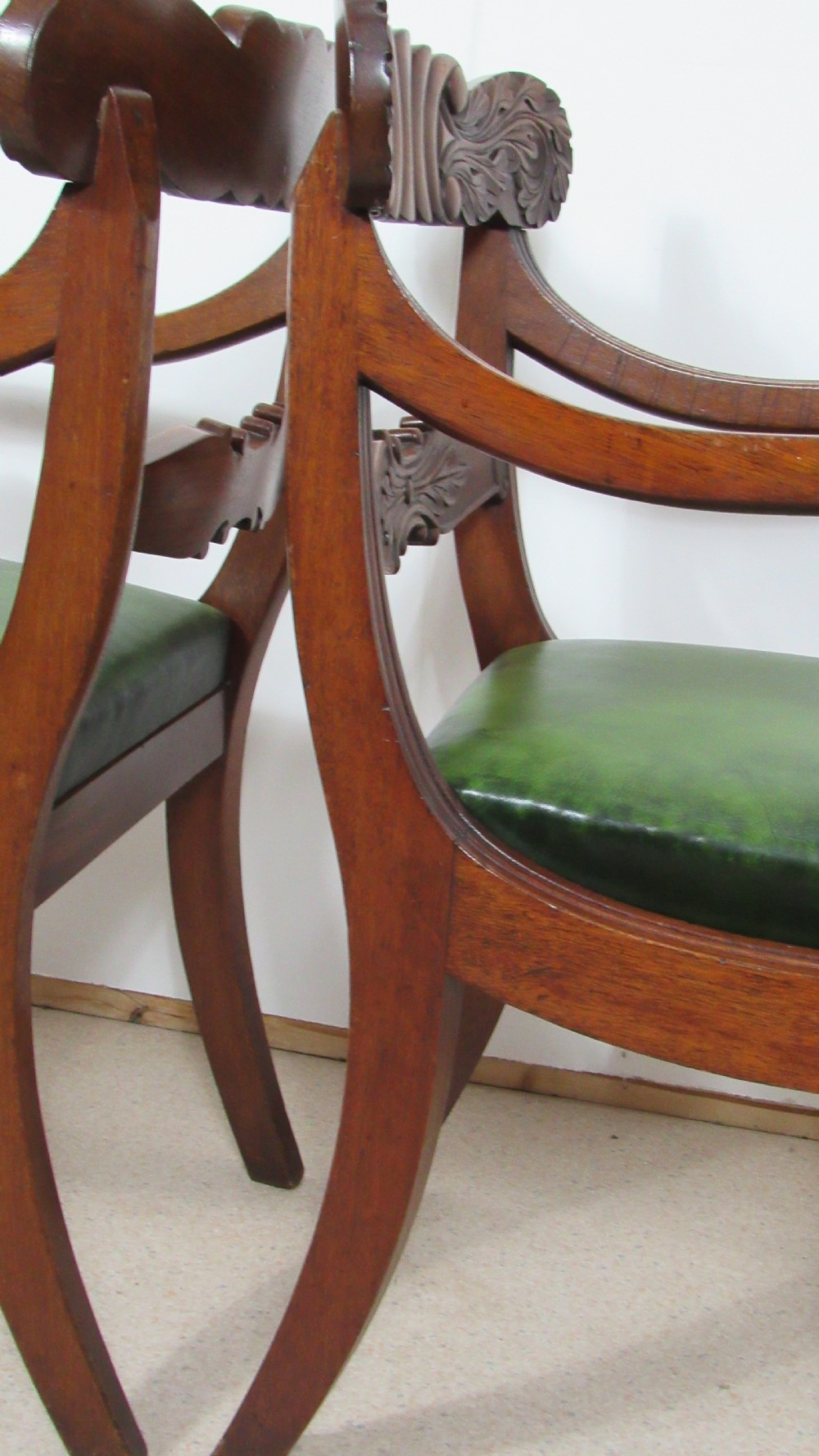 A pair of carved mahogany armchairs featuring scroll-carved top rails, curved armrests, reeded front rails, and green leather upholstered seats. View VI