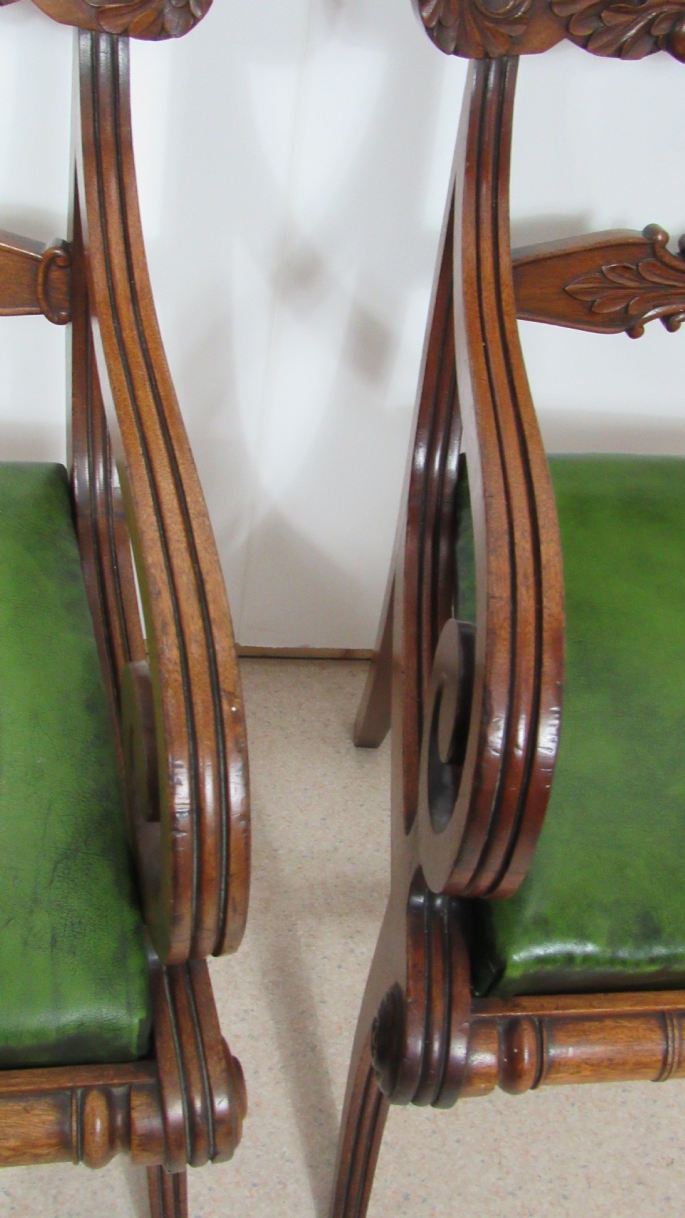 A pair of carved mahogany armchairs featuring scroll-carved top rails, curved armrests, reeded front rails, and green leather upholstered seats. View XV