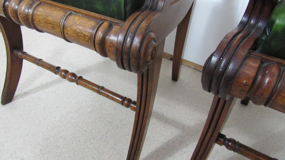 A pair of carved mahogany armchairs featuring scroll-carved top rails, curved armrests, reeded front rails, and green leather upholstered seats. View XVI