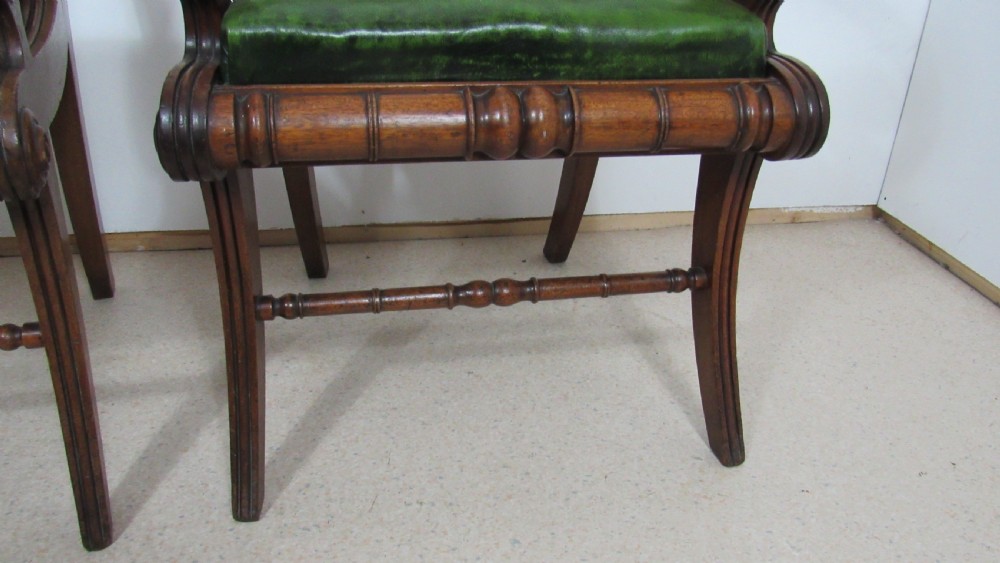A pair of carved mahogany armchairs featuring scroll-carved top rails, curved armrests, reeded front rails, and green leather upholstered seats. View XVII