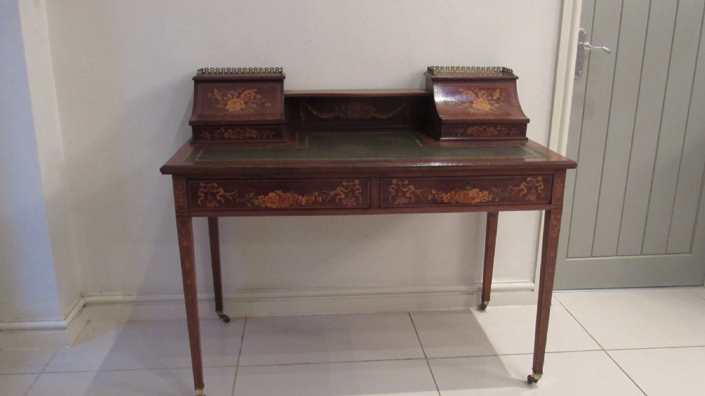 An Edwardian mahogany writing desk featuring detailed floral marquetry inlays, a green leather top, and raised stationery boxes with brass galleries. View II
