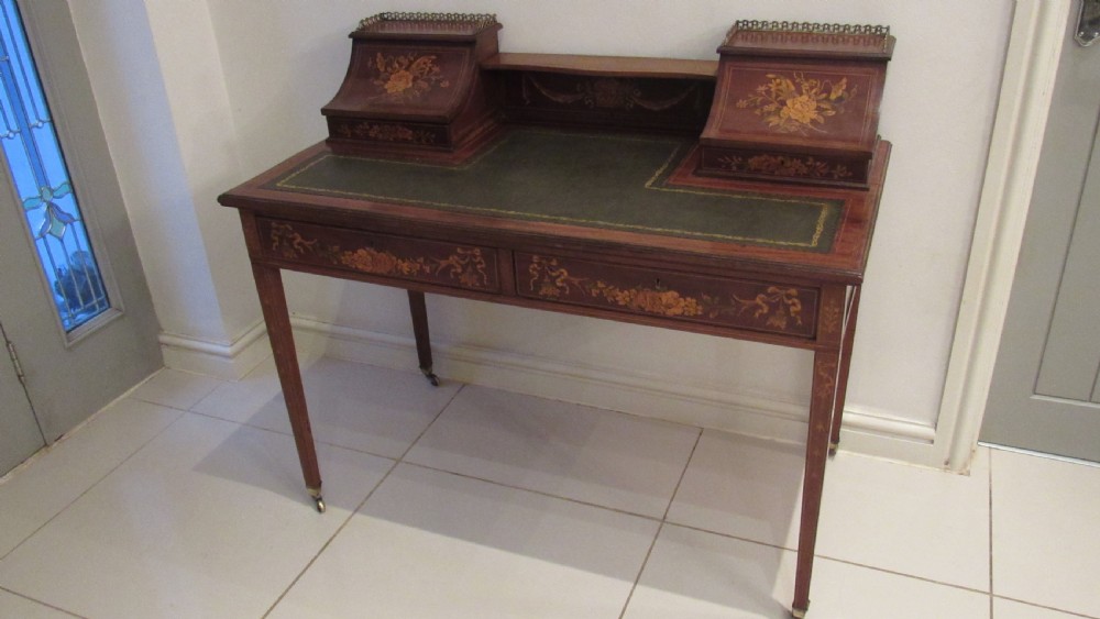 An Edwardian mahogany writing desk featuring detailed floral marquetry inlays, a green leather top, and raised stationery boxes with brass galleries. View III